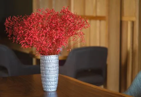Beautiful silver vase with sand texture and red-colour plant in wooden table 스톡 사진