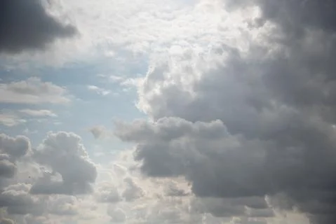 Beautiful sky background. Light blue sky with dramatic white and gray clouds. Stock Photos