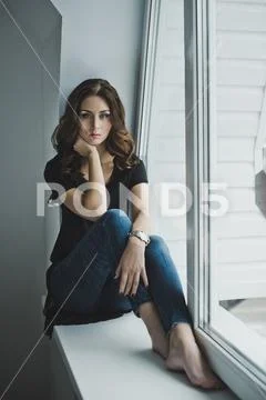 A beautiful slender girl sits on the windowsill 4965. Stock Photos
