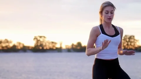 Beautiful, slender young blond woman engaged in fitness, jumps, performs Stock Footage