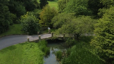 Beautiful small bridge over small river with green surroundings, drone aerial 4K Video stock 101140607