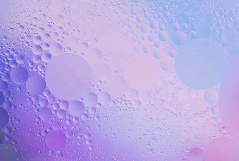 Beautiful small bubbles of oil on surface of the water. Delicate cosmetic violet Stock Photos