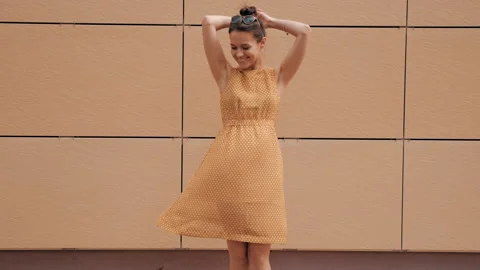 Beautiful smiling brunette model posing near yellow wall in dress Stock Footage 141810727