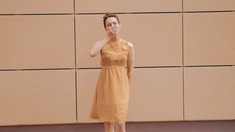 Beautiful smiling brunette model posing near yellow wall in dress 库存影片 141810866