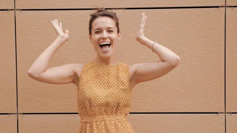 Beautiful smiling brunette model posing near yellow wall in hipster dress Stock Footage 141810897