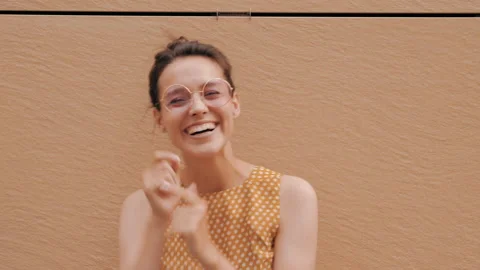 Beautiful smiling brunette model posing near yellow wall in hipster dress Stock Footage 141811243