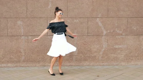 Beautiful smiling brunette model posing near wall in dress Stock Footage 141904033