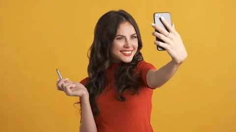 Beautiful smiling girl with red lipstick happily taking selfie on smartphone Stock Photos