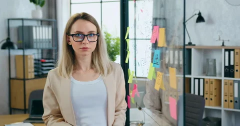 Beautiful smiling successful skilled blond woman standing near transparent board Stock Footage 157991220