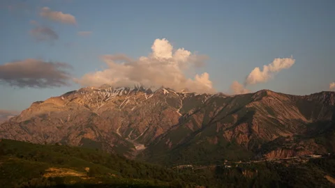 Beautiful snow-capped mountains, clouds fly over the peaks at sunset. Timelapse. Stock Footage 240291601