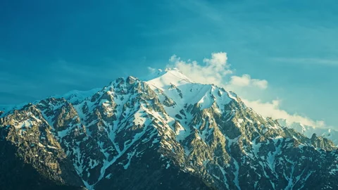 Beautiful snow-capped mountains, clouds fly over the peaks at sunset.Timelapse. Stock Footage 241571953