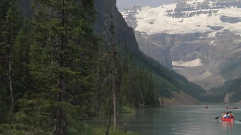 Beautiful snow covered mountain and tourists kayaking on lake Stock Footage 99080695