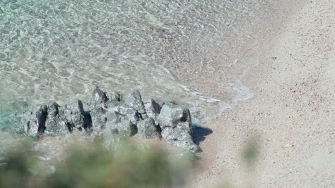 Beautiful soft waves run over rocks and sand. Clear blue water with sun glare Stock Footage 154711357