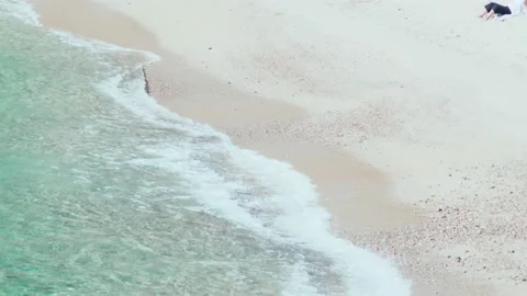 Beautiful soft waves run over rocks and sand. Clear blue water with sun glare Stock Footage 154822685