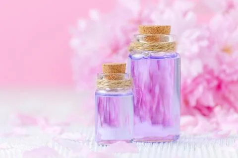 Beautiful spa composition with two bottles of aroma oils, fresh flowers on pink Stock Photos