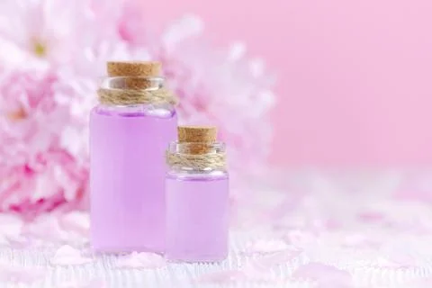 Beautiful spa composition with two bottles of aroma oils, fresh flowers on pink Stock Photos