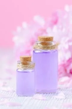 Beautiful spa composition with two bottles of aroma oils, fresh flowers on pink Stock Photos