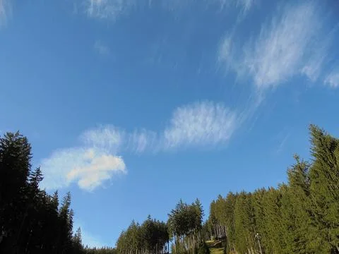 Beautiful sparse clouds on a blue sky over mountain forests. Stock Photos