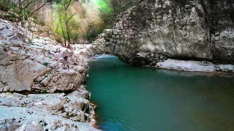 Beautiful stone semi-arch bridge over a river with blue water in the mountains Stock Footage 270062409