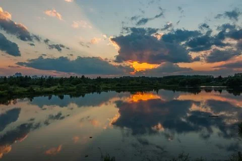 A beautiful summer evening. The dramatic sunset reflects in the smooth water Stock Photos