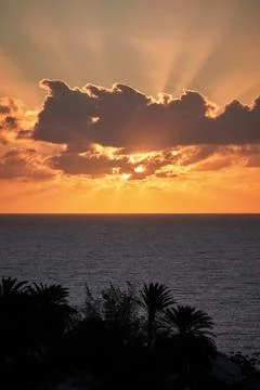 The beautiful sun behind clouds rises brilliantly over the Atlantic Ocean i.. Stock Photos