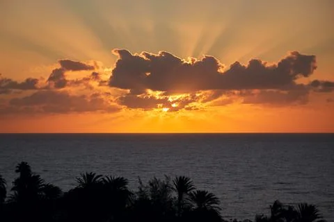 The beautiful sun behind clouds rises brilliantly over the Atlantic Ocean i.. Stock Photos