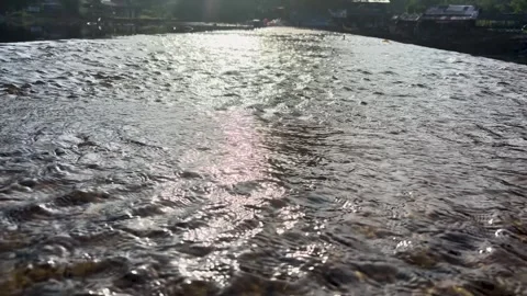 Beautiful sun glint and ripples on flowing river water surface at sunset. Stock Footage 346012885
