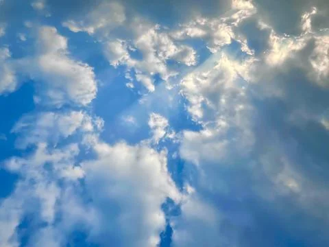 Beautiful Sun Rays Breaking Through Fluffy White Clouds in a Vibrant Blue Sky Stock Photos