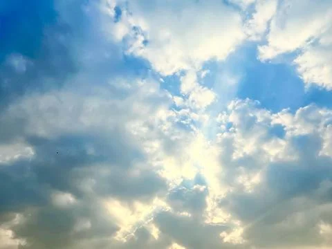 Beautiful Sun Rays Breaking Through Fluffy White Clouds in a Vibrant Blue Sky Stock Photos