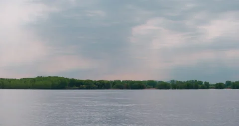 Beautiful sun rays in a colorful cloudy sky at the lake / Panning left Stock Footage 130989135