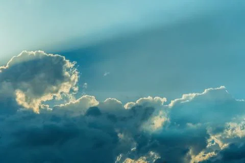 Beautiful sun rays shining through storm clouds remainings on blue sky. Stock Photos