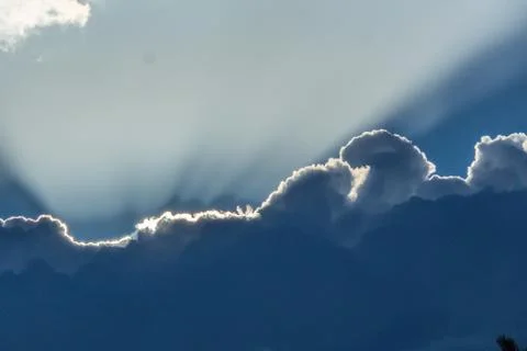 Beautiful sun rays shining through storm clouds remainings on blue sky. Foto stock