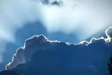 Beautiful sun rays shining through storm clouds remainings on blue sky. Stock Photos