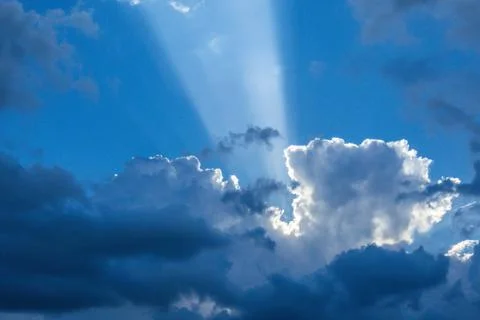 Beautiful sun rays shining through storm clouds remainings on blue sky. Stock Photos