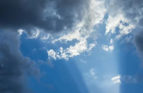 Beautiful sun rays shining through storm clouds remainings on blue sky. Stock Photos