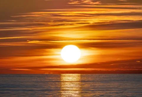 The beautiful sun is setting gracefully over a tranquil body of water Stock Photos