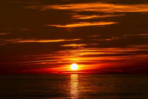 The beautiful sun is setting gracefully over a tranquil body of water Stock Photos