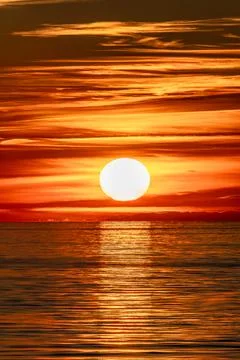 The beautiful sun is setting gracefully over a tranquil body of water Stock Photos