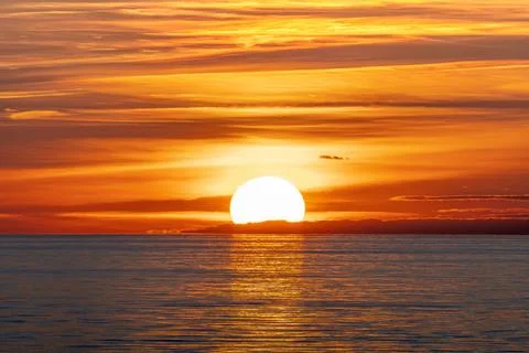 The beautiful sun is setting gracefully over a tranquil body of water Stock Photos