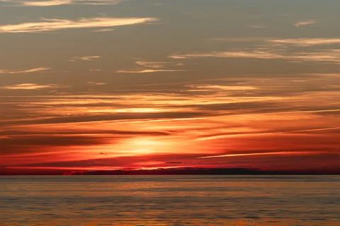 The beautiful sun is setting gracefully over a tranquil body of water Stock Photos