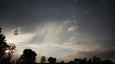 Beautiful sunbeams breaking through dramatic clouds at sunset Stock Photos