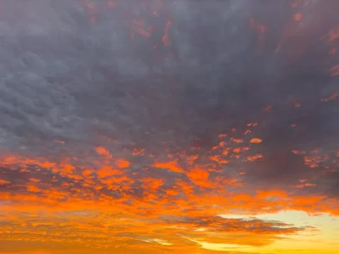 A beautiful sunset adorned with numerous clouds scattered across the sky Stock Photos