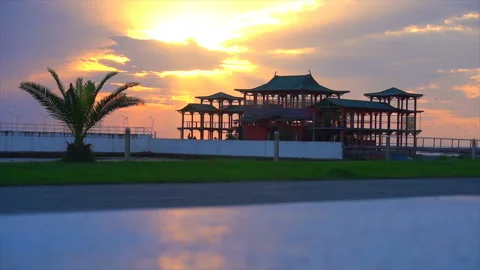 Beautiful sunset against the backdrop of palm trees and chinese house Stock Footage 94137859