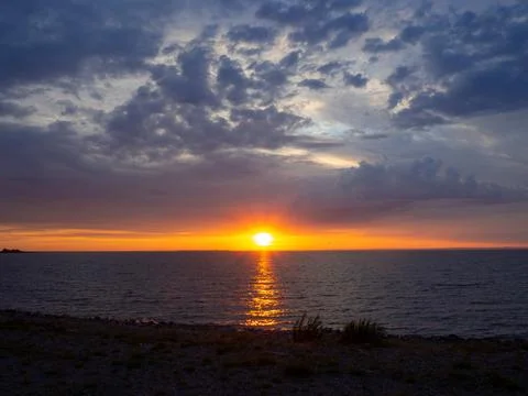 Beautiful sunset at the beach. Dramatic sky with clouds. Sunlight is reflec.. Stock Photos