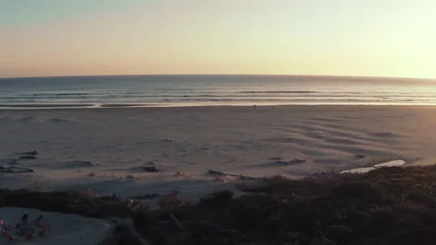 Beautiful sunset on a beach with rocky cliffs in the distance aerial drone shot Stock-Footage 153208179
