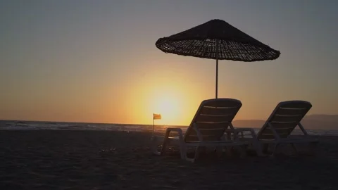 Beautiful sunset beach scene with two chairs on sandy beach against sea. Stock Footage 154952969