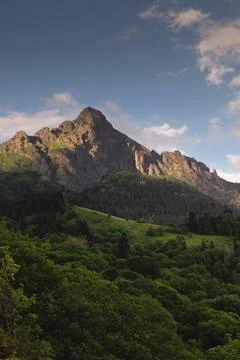 A beautiful sunset behind a mountain range at the base of which is a green dense Stock Photos