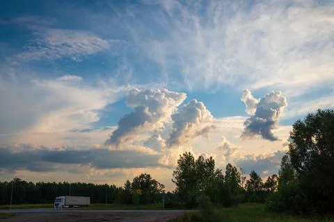 Beautiful sunset clouds on the background of forest and road Stock Photos