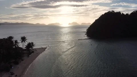 Beautiful sunset from a drone view over a Philippine beach, next to a small isla Stock Footage 245532308