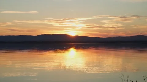 Beautiful sunset on the lake. Mirror reflection of the sky on the water. Stock Footage 250233838